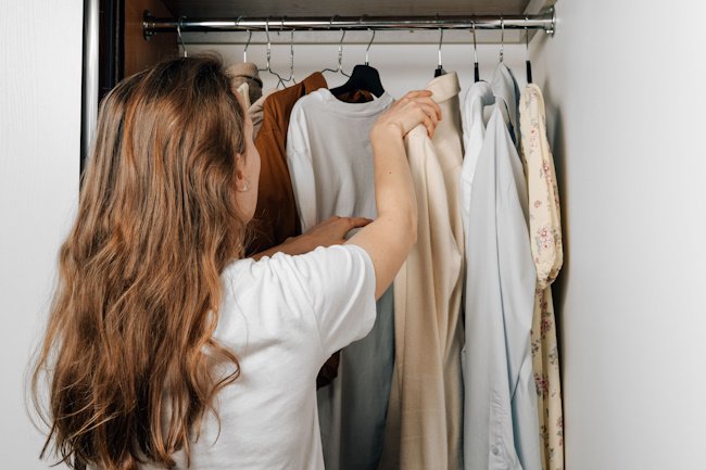 девушка ищет одежду в шкафу